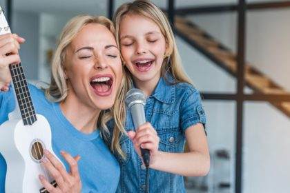 Caucasian mother with little girl singing in karaoke at home