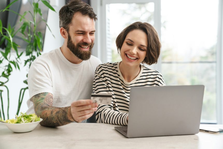 Portrait of a cheerful couple shopping online with laptop computer