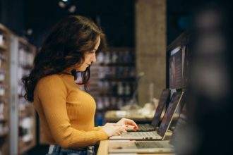 Smart modern female customer choosing laptop in the computer shop. difficult decision.