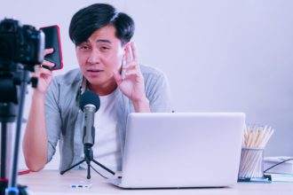 Young asian man selling digital gadgets on social media by streaming live from his home.