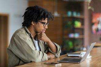 Young Black Male Entrepreneur Working With Laptop At Modern Coffeeshop